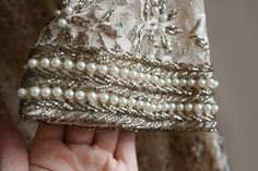 a hand holding a purse with pearls on it