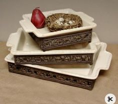 three trays with birds nest and one red apple sitting on top of each other