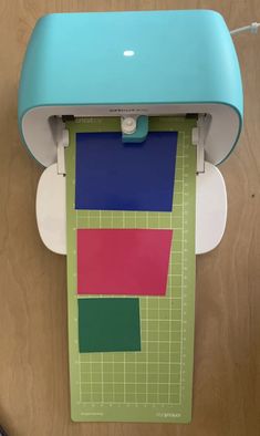 a blue and green cutting mat sitting on top of a wooden table next to a computer mouse