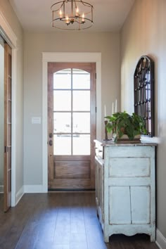 an entryway with a wooden door and light fixture