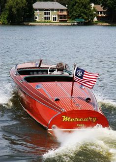 a red speed boat with an american flag on it's side in the water