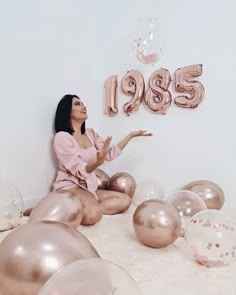 a woman is sitting on the floor surrounded by balloons and helium letters that spell her birthday