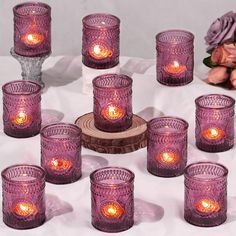 a group of purple glass candles sitting on top of a table