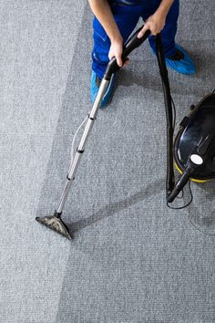 a person using a vacuum to clean carpet