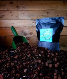 a pile of dirt next to a shovel and bag of coffee beans on the ground