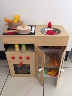 a wooden toy kitchen playset with various foods and cooking utensils in it