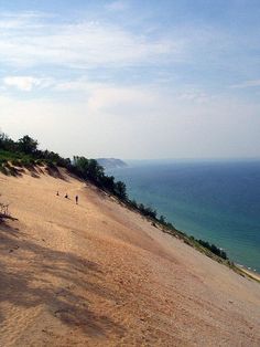 two people are walking on the beach by the water