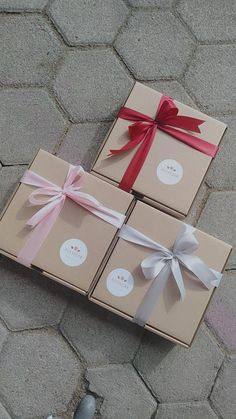 three boxes wrapped in brown paper with red and white ribbons tied around them on the ground