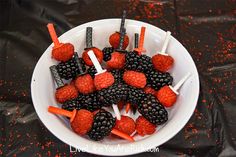 berries and marshmallows are arranged on sticks in a bowl