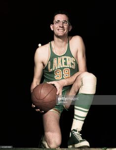 a man holding a basketball sitting on top of a wooden bench in front of a black background