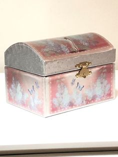 a pink and silver box sitting on top of a white table next to a wall