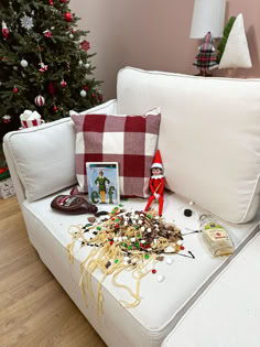 a white couch with christmas decorations on it next to a christmas tree and other items