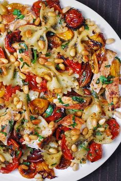 a white plate topped with pasta and veggies on top of a wooden table