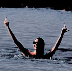 a man swimming in the water with his arms up and one hand raised above his head