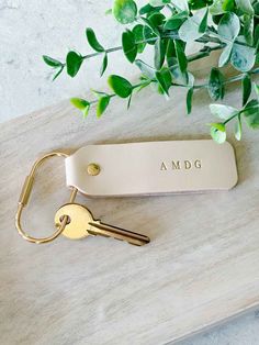 a keychain with the word amdg on it next to a plant