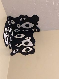 a black and white clock hanging from the side of a wall with eyes on it