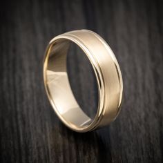 a gold wedding ring sitting on top of a wooden table