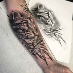 a man's arm with a tiger and bamboo plant tattoo on the left forearm