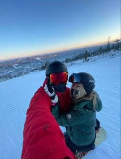 two people sitting in the snow with their arms around each other