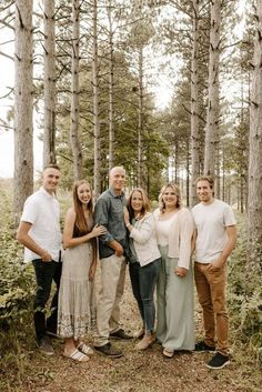 a group of people standing next to each other in front of some tall pine trees