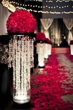 red rose petals in vases with lights and draping on the floor behind them