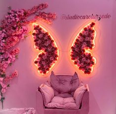 a pink chair sitting in front of a butterfly shaped wall with flowers on the walls