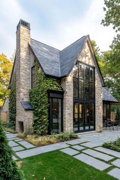 a stone house with large windows and lots of greenery on the front lawn area