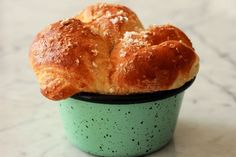 two croissants sitting in a green cup on a marble counter top with white speckles