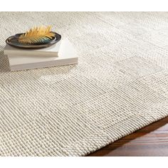 a white rug with a black plate on top of it next to a stack of books