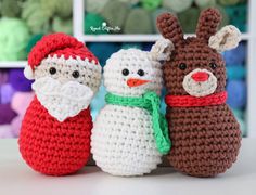 three crocheted snowman and reindeer dolls sitting next to each other on a table