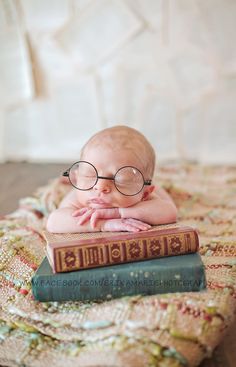 a baby wearing glasses laying on top of a book