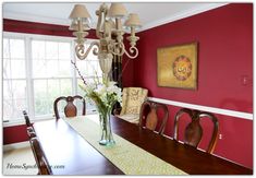 a dining room with red walls and white trim