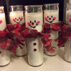 six decorated candles are sitting on a table with red bows and snowmen painted on them