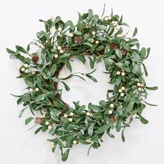 a green wreath with white berries and pine cones