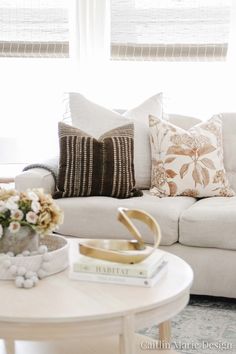 a living room filled with furniture and pillows on top of a white table in front of a window