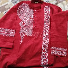 a red shirt with white designs on the front and back, sitting on top of a bed