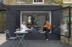 a family sitting on the back deck of a house with their child and adult looking out