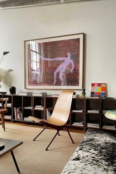 a living room filled with furniture and a painting hanging on the wall above it's bookshelf