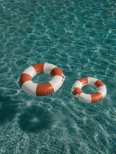 two life preservers floating on top of a body of water with no one in it