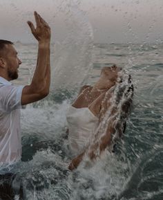 a man and woman are in the water with their hands up to each other as they float