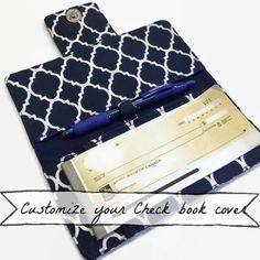 a blue and white patterned book with a pen on it, next to a checkbook cover