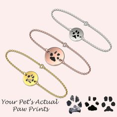 three dog paw prints are shown on two different bracelets and one is gold, the other silver