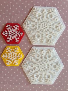 three plastic hexagons with beaded designs on them sitting on a polka dot tablecloth