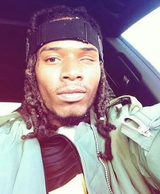 a man with dreadlocks sitting in the back seat of a car looking at the camera