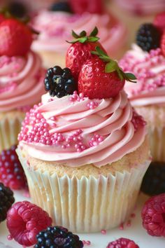 cupcakes with pink frosting and fresh berries on top, surrounded by raspberries