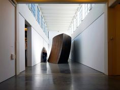 a woman is standing in an empty hallway next to a large piece of art on the wall