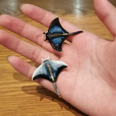 two starfish shaped rings sitting on top of a person's hand with their fingers in the air