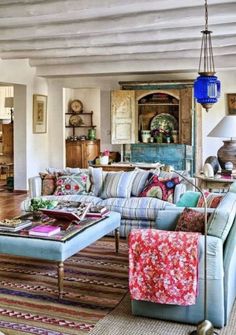 a living room filled with furniture and lots of pillows on top of a wooden floor