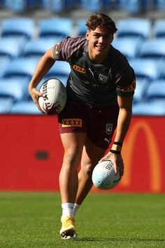 a man holding a rugby ball on top of a field