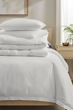 a stack of white pillows on top of a bed